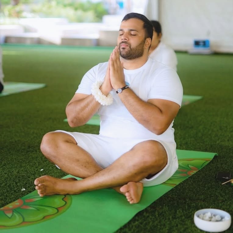 Person practicing yoga outdoors on a green mat